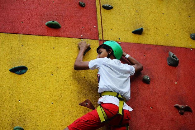 Photo low angle view of boy climbing wall