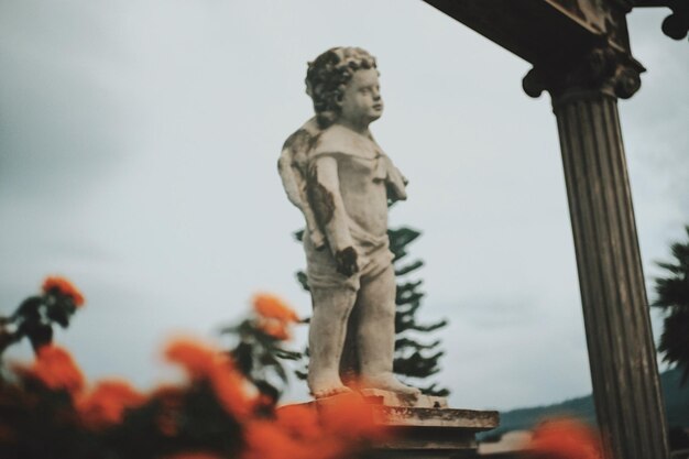 Low angle view of boy statue against sky