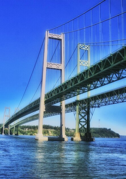 Low angle view of bridge over river against blue sky