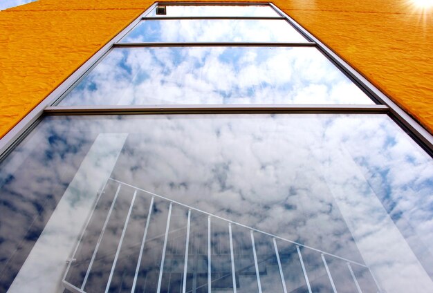 Photo low angle view of building windows with clouds reflection