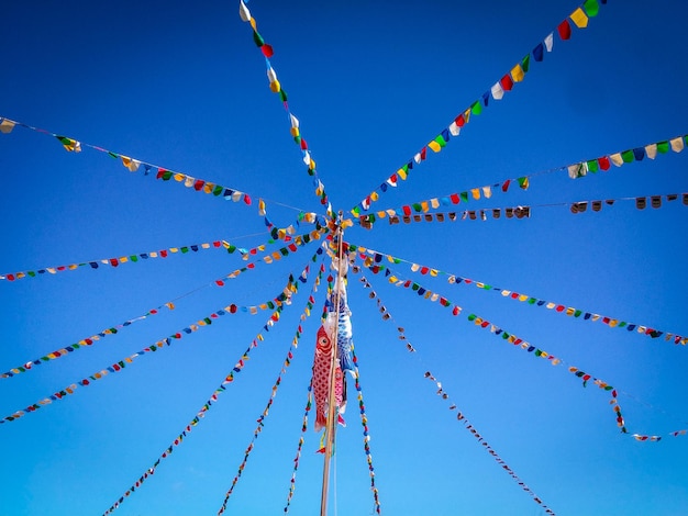 Low angle view of buntings hanging against clear blue sky