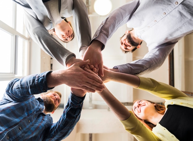 low angle view of businesspeople stacking hand together at workplace