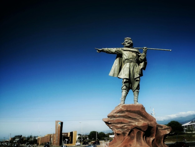 Photo low angle view of chacho penaloza statue against clear blue sky