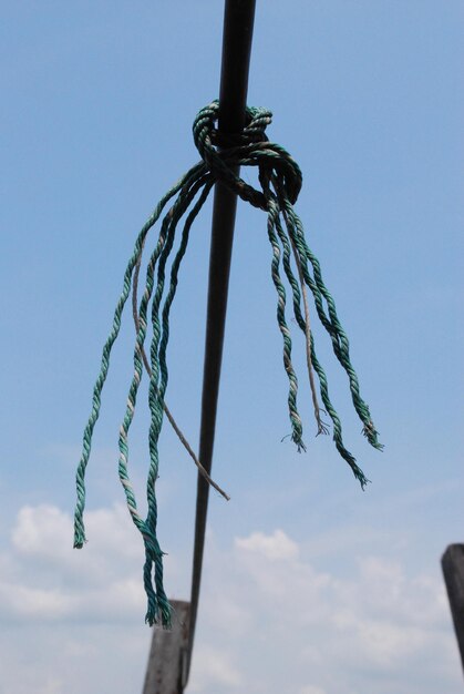 Low angle view of chain hanging against blue sky