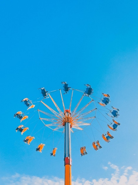 Low angle view of chain swing ride against blue sky