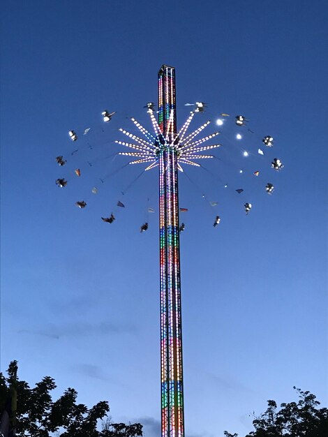 Low angle view of chain swing ride against clear blue sky