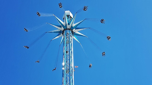 Low angle view of chain swing ride against clear blue sky