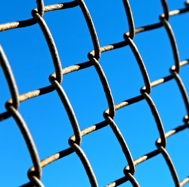 Foto vista a basso angolo della recinzione a catena contro un cielo blu limpido