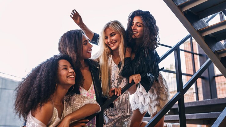 Photo low angle view of cheerful female friends standing on staircase