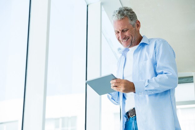 Low angle view of cheerful mature man holding tablet