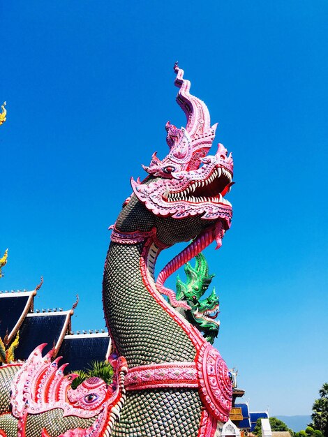 Low angle view of chinese dragon statue against blue sky