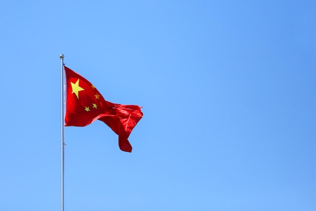 明るい青い空の背景にある中国国旗の低角度の写真