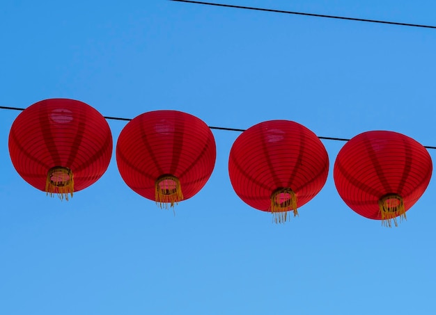 Low angle view of chinese lanterns hanging against clear blue sky