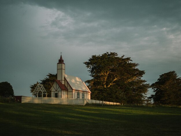 Photo low angle view of church by field against cloudy sky