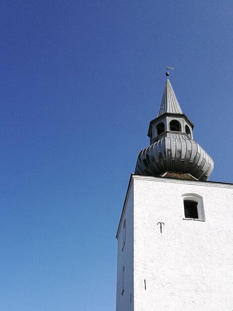 Low angle view of church tower against clear blue sky