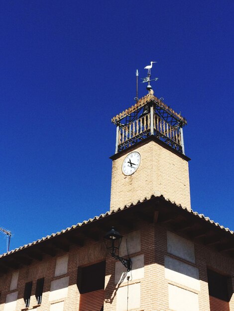 Low angle view of clock tower against clear blue sky