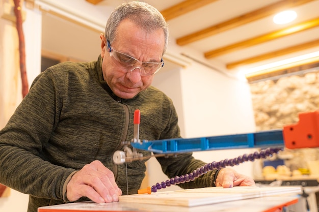 Low angle view closeup of a concentrated carpenter cutting a piece of wood in workshop