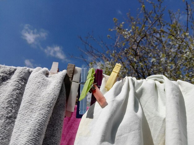 青い空を背景に衣類のラインで乾燥する服の低角度の景色