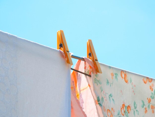 Low angle view of clothes hanging on clothesline against blue sky