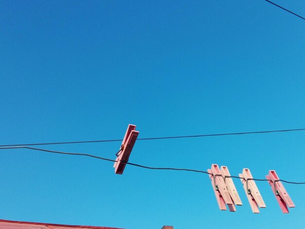 Low angle view of clothes hanging on clothesline against blue sky