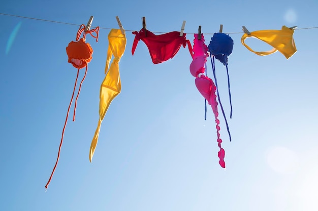 Low angle view of colorful female swimwear hanging against the blue sky