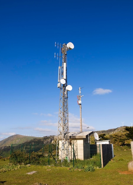 Low angle view of communications tower on field against blue sky