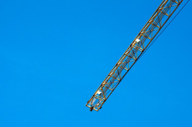 Low angle view of crane against clear blue sky