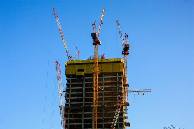 Low angle view of crane against clear blue sky