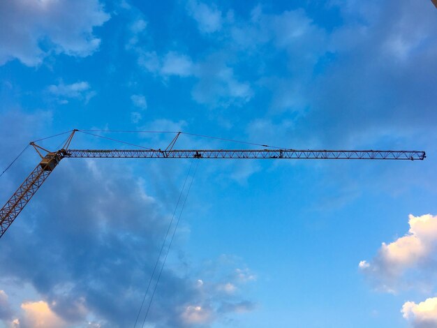 Low angle view of crane against cloudy sky