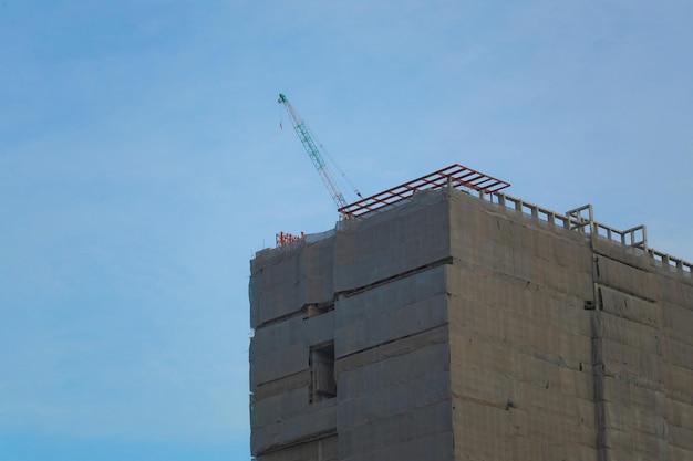 Low angle view of crane by building against clear blue sky