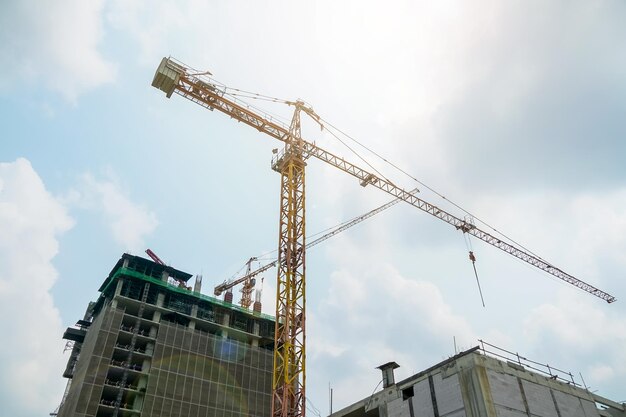 Low angle view of crane by building against sky