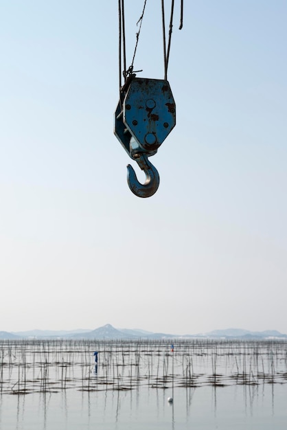 Vista a basso angolo di un gancio di gru sul mare contro un cielo limpido