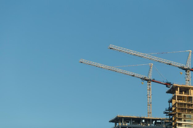 Low angle view of cranes against clear blue sky