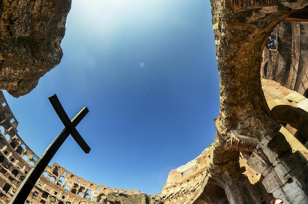 Low angle view of cross at coliseum against sky