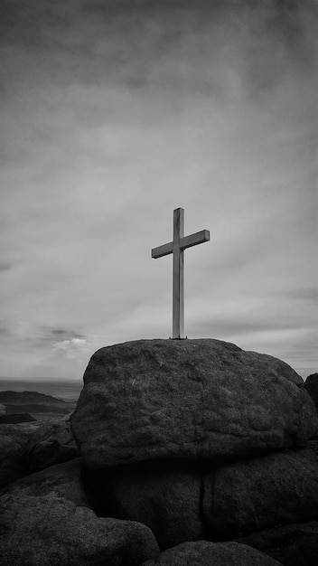 Photo low angle view of cross on rock against sky