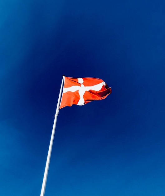 Low angle view of danish flag against blue sky