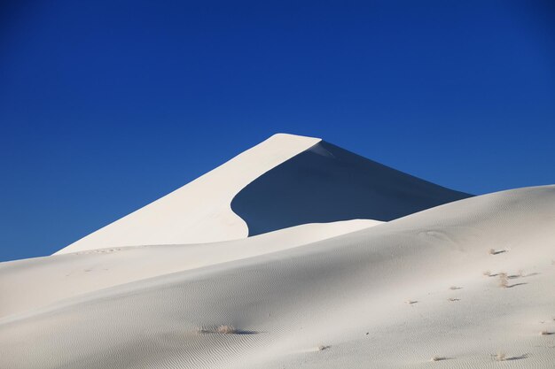 Low angle view of desert against clear blue sky