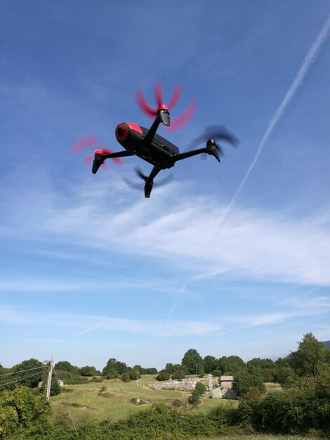 Foto vista a bassa angolazione di un drone che vola contro il cielo blu