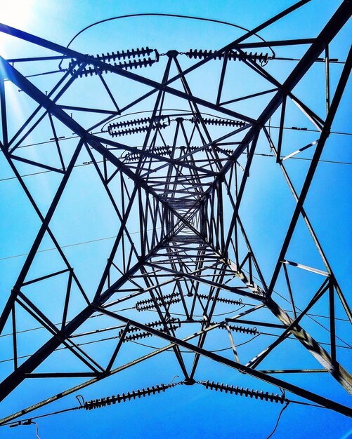 Low angle view of electricity pylon against blue sky