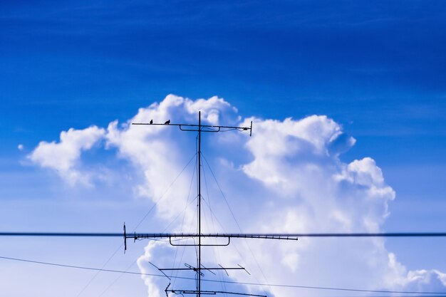 Low angle view of electricity pylon against blue sky