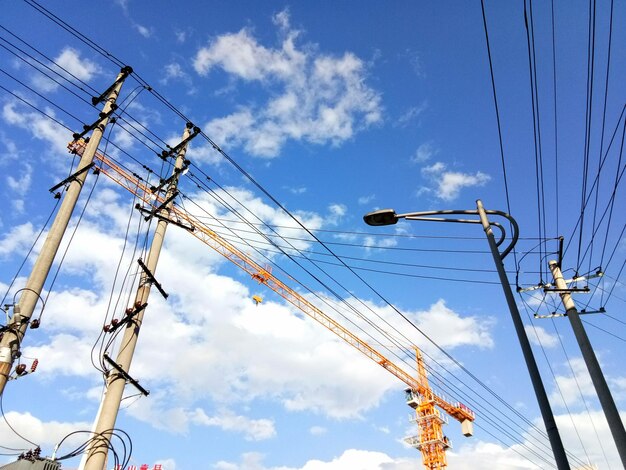 Low angle view of electricity pylon against blue sky