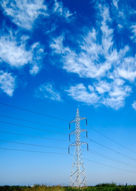 Low angle view of electricity pylon against blue sky