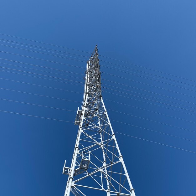 Low angle view of electricity pylon against blue sky