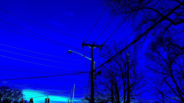 Low angle view of electricity pylon against blue sky