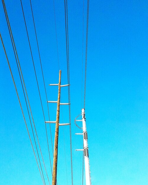 Low angle view of electricity pylon against clear blue sky