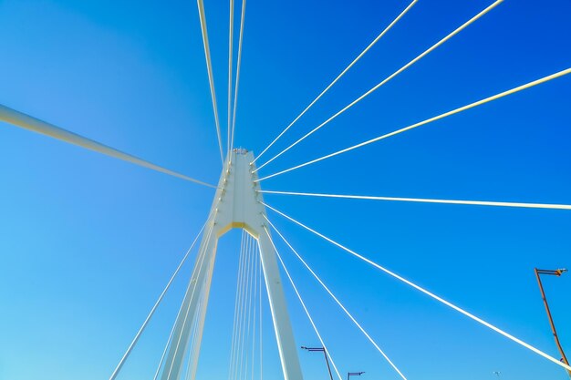 Low angle view of electricity pylon against clear blue sky