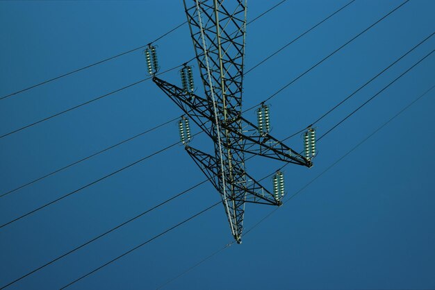 Low angle view of electricity pylon against clear blue sky