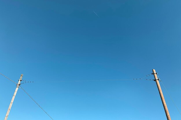 Low angle view of electricity pylon against clear blue sky