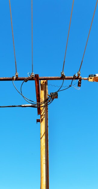 Low angle view of electricity pylon against clear blue sky