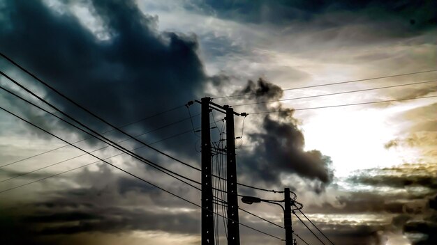 雲の空に照らされた電気柱の低角度の景色